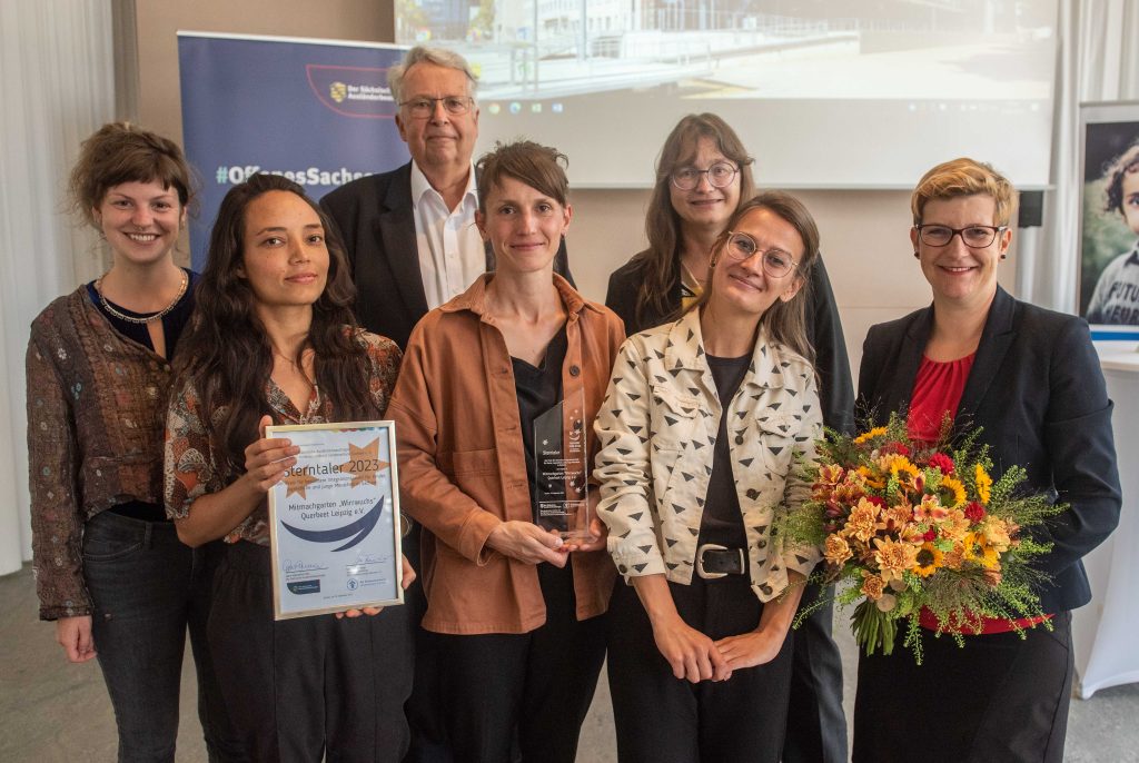 Mitarbeiterinnen des Projektes mit einer Urkunde, dem Preis und Blumen, neben Gert Mackenroth, Silke Brewig-Lange, Susann Rüthrich
